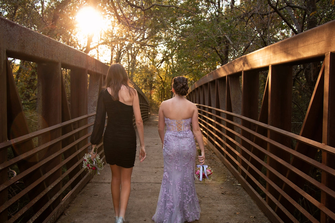 Two women in formal dresses walking on a bridge