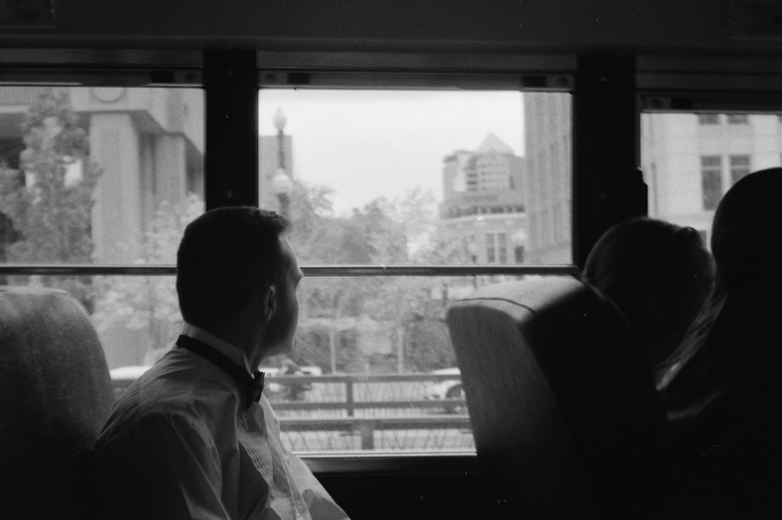 Man in formal wear looks out bus window